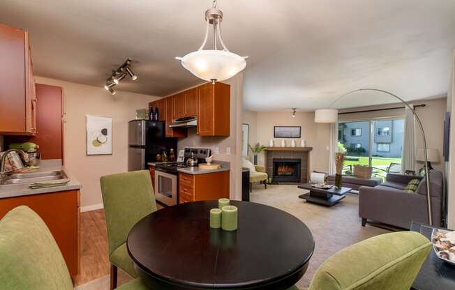 a living room with a dining room table and chairs and a fireplace in the background