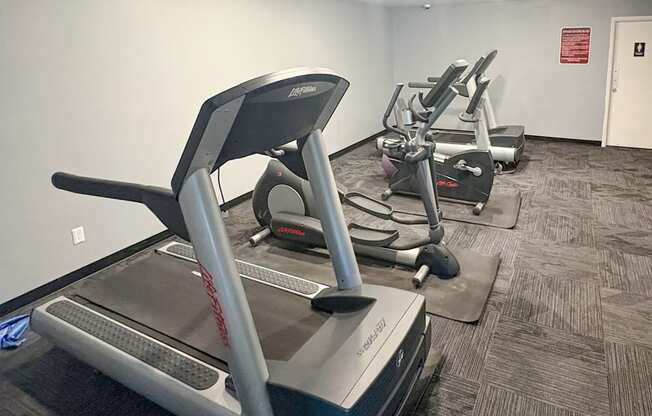 A treadmill in a gym with a grey carpet.