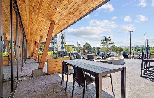 A wooden table with chairs is set up outside on a patio.