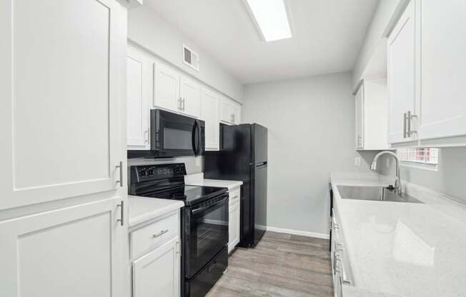 A kitchen with black appliances and white cabinets.