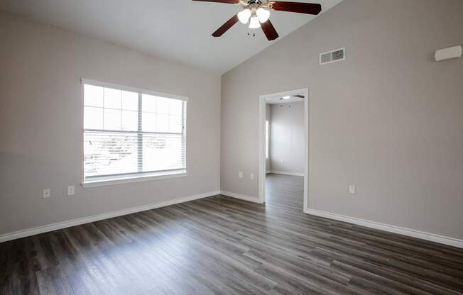 A room with a ceiling fan and a window with blinds.