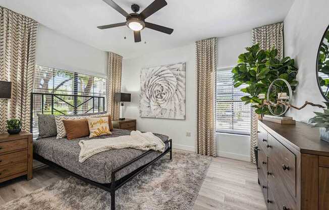 A bedroom with a bed, dresser, and ceiling fan.