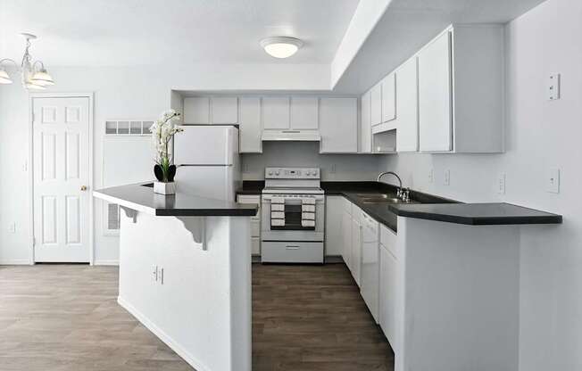 A kitchen with white cabinets and a black countertop. at Oakstone Apartments, Clearfield, 84015