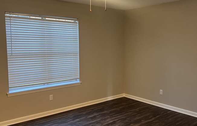 an empty living room with a large window and a ceiling fan