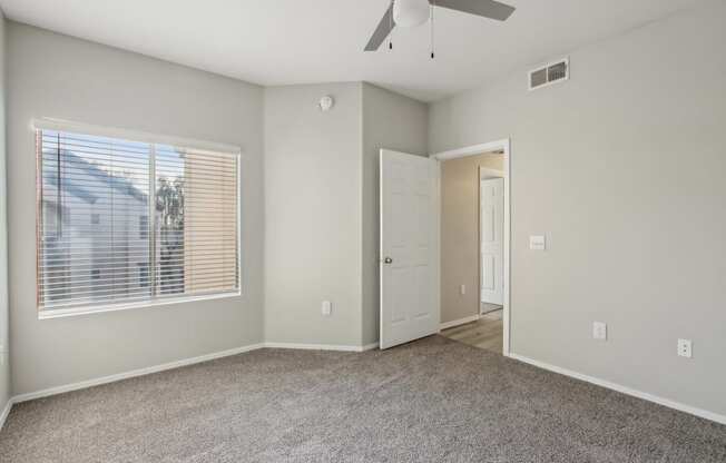 A room with a ceiling fan and a window with blinds.