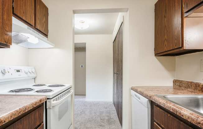 a kitchen with white appliances and wooden cabinets and a white stove top oven