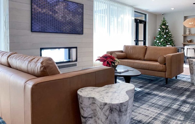 a community room with leather couches in front of a fireplace seating area