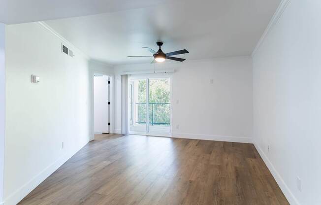 A room with a ceiling fan and sliding glass doors.