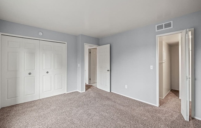 an empty bedroom with blue walls and white doors