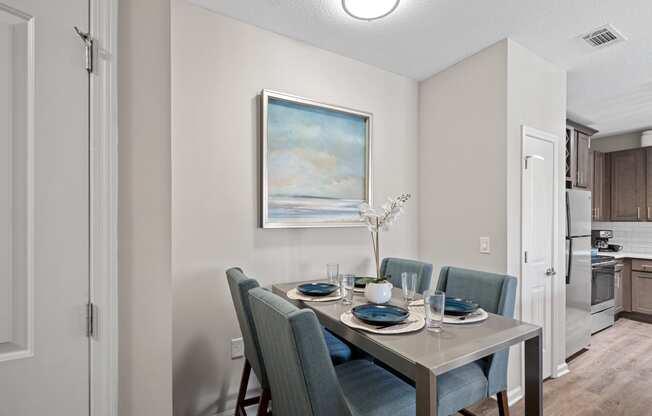 a dining room with a table and chairs and a painting on the wall