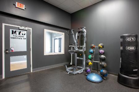 A gym room with a weight rack, a punching bag, and a window.