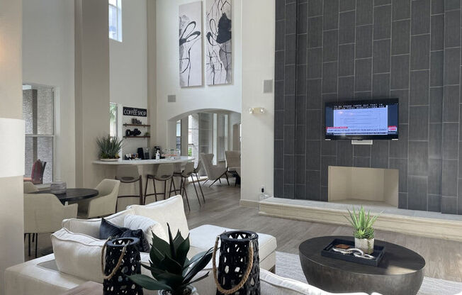 A modern living room with a white sofa set and a TV mounted on the wall.