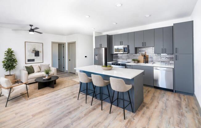 Open-concept kitchen and living area with a large island, stainless steel appliances, design-forward tile backsplash, and wood-style flooring throughout.