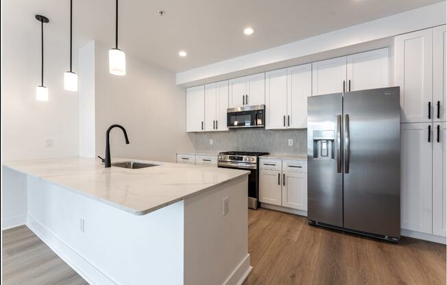 A modern kitchen with a white countertop and stainless steel appliances.