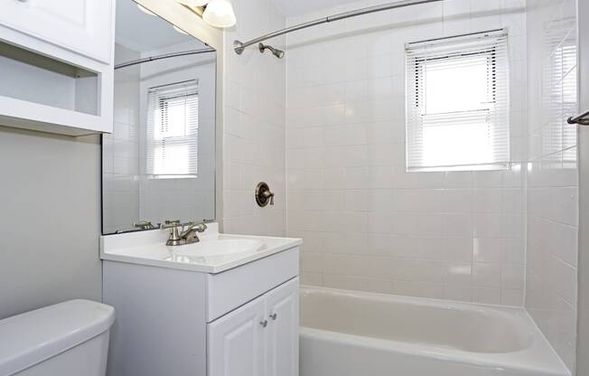 A white bathroom with a tub, sink, and mirror.