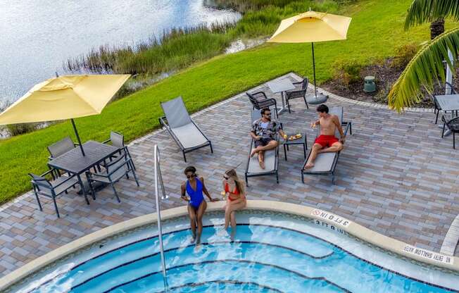A group of people are enjoying a sunny day by the pool.