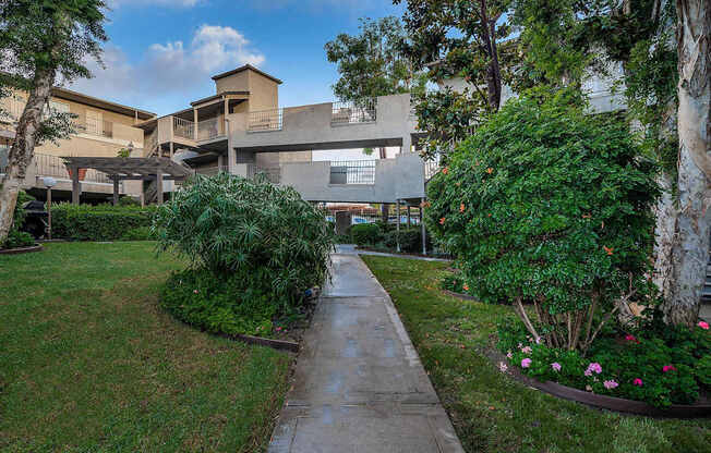 A concrete pathway leads to a building surrounded by greenery.