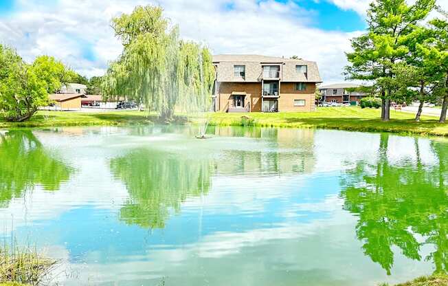 A serene lake in front of a building surrounded by trees.