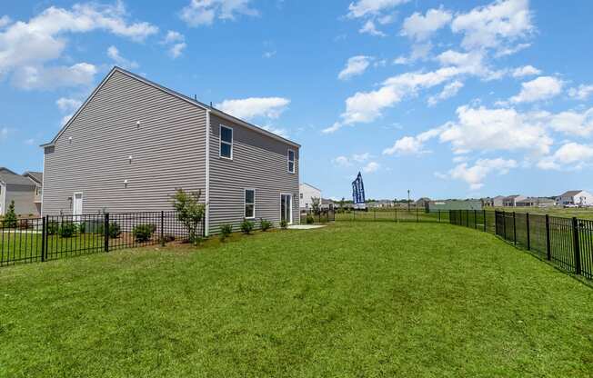 a backyard with a large lawn and a house in the background