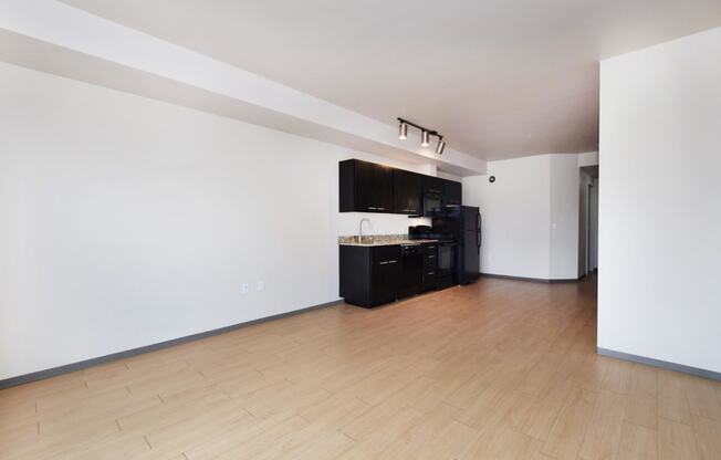 an empty living room with a hardwood floor and white walls