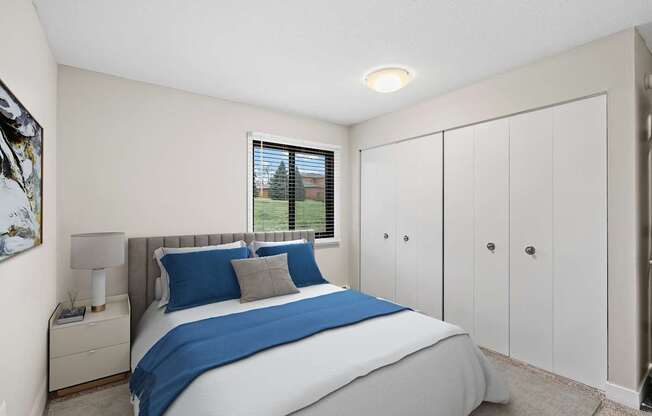 A bedroom with a large bed and a window with blinds.
