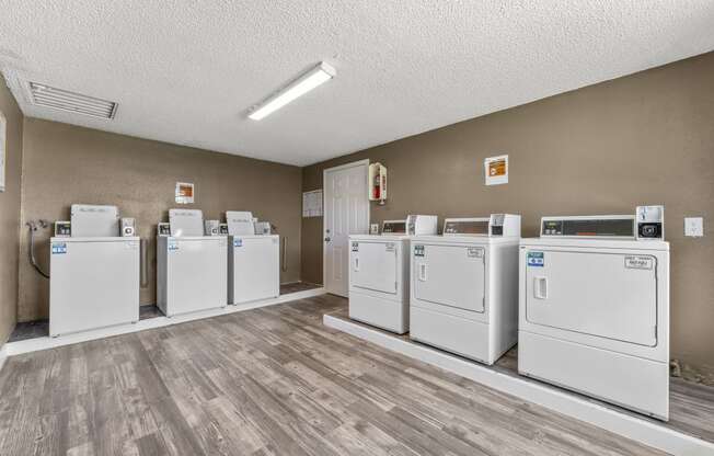 a row of washers and dryers in a laundry room with wood floors