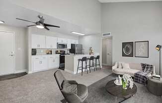 Model Living Room with Carpet and View of Kitchen with Wood-Style Flooring at Crystal Creek Apartments in Phoenix, AZ.