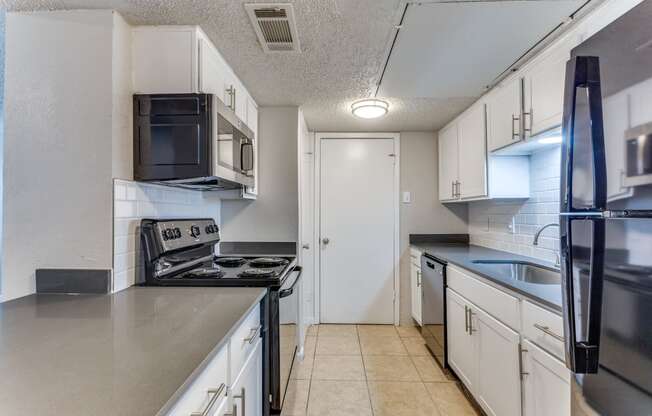 an empty kitchen with white cabinets and stainless steel appliances