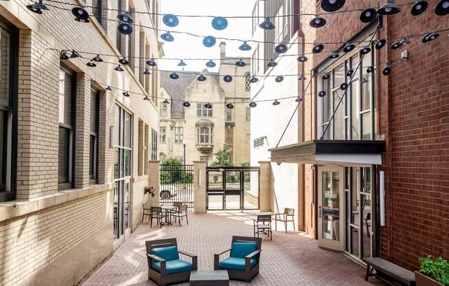 a courtyard with blue chairs and a red brick building in the background