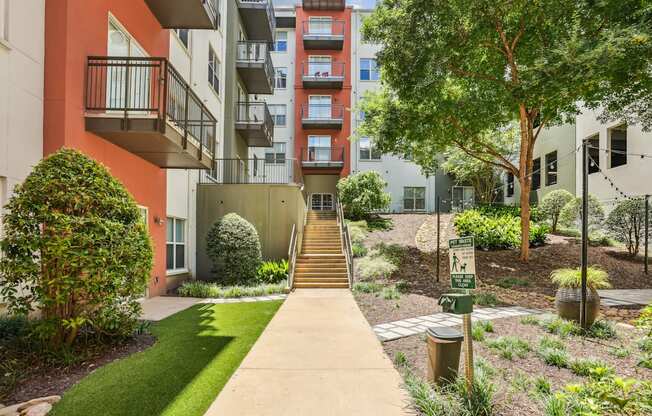A pathway leads up a set of stairs in a landscaped courtyard.