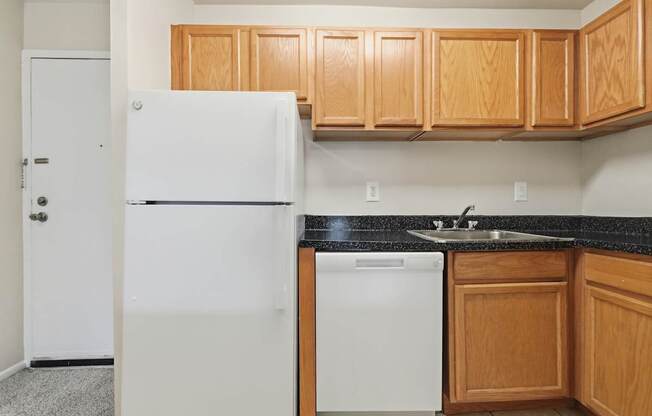 A white refrigerator is in a kitchen with wooden cabinets.