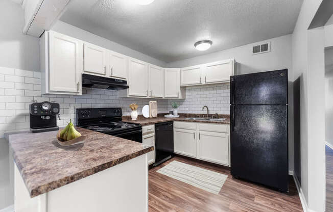 Overland Park, KS Apartments – Treetop Lodge – A kitchen with black appliances and white cabinets.