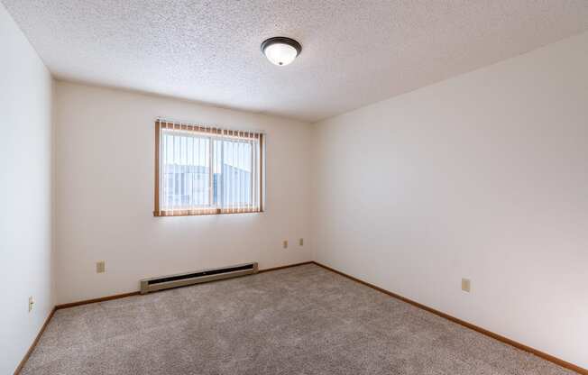 a bedroom with carpet and a window. Grand Forks, ND Chandler 1866 Apartments