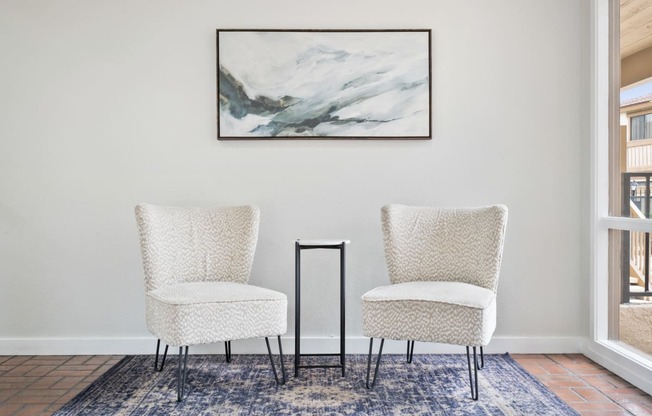 two chairs in a living room with a painting on the wall