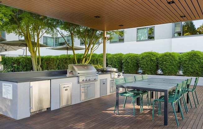 the outdoor kitchen has stainless steel appliances and a table with chairs