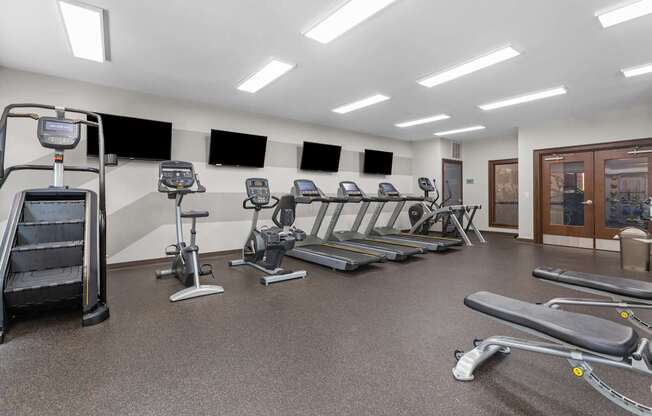 A gym with treadmills, elliptical machines, and a stair climber.