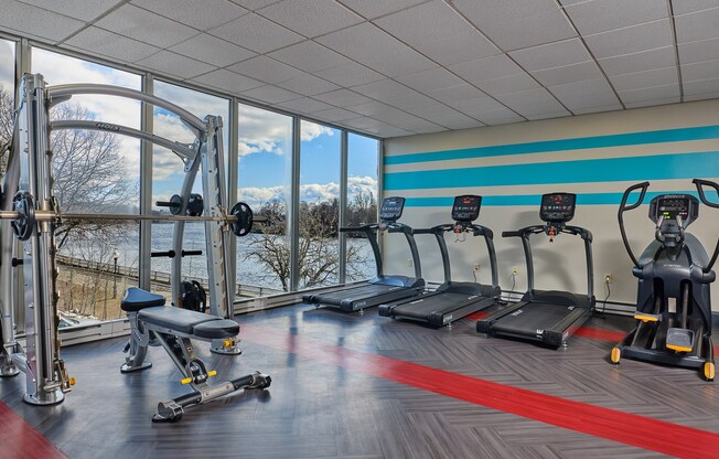 The atherton gym with cardio equipment, smith machine, bench, elliptical, view of river