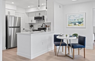 an open kitchen and dining area with a table and chairs and a refrigerator