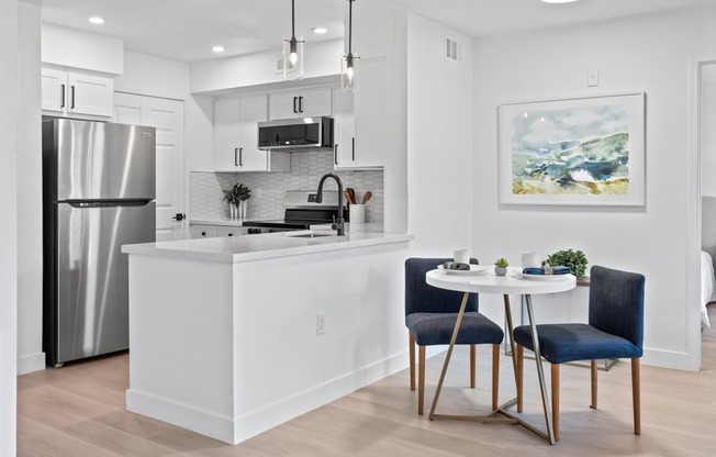 an open kitchen and dining area with a table and chairs and a refrigerator