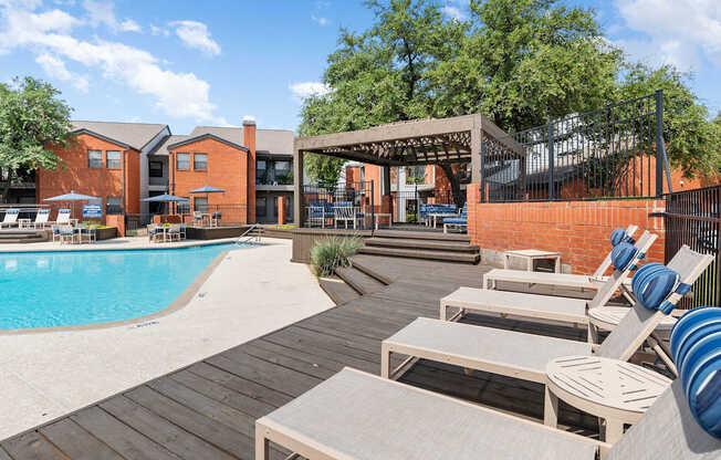 Pool deck with lounge chairs, pergola seating, and landscaped surroundings at Heritage at Valley Ranch.