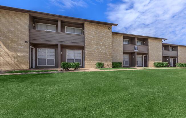 a large brick building with grass in front of a house