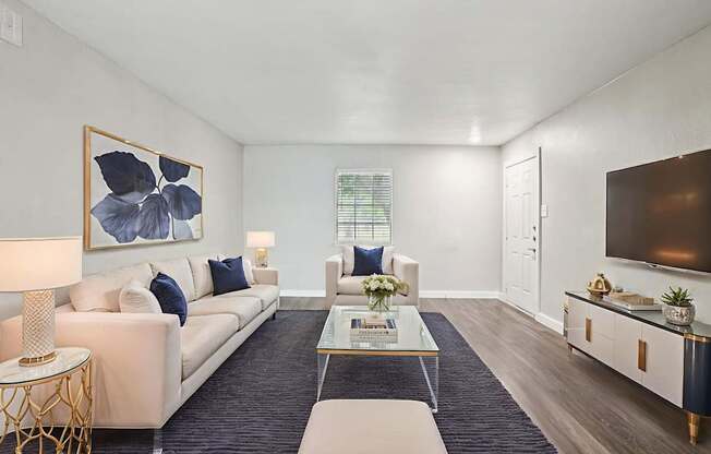 A living room with a white sofa, a coffee table, and a painting on the wall.