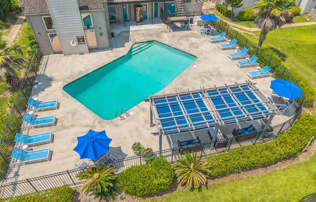 A large swimming pool surrounded by sun loungers and umbrellas.
