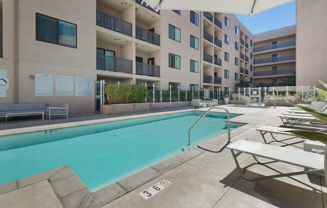 A pool area with a pool and sun loungers.