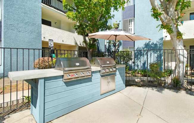 the outdoor kitchen has two grills and an umbrella