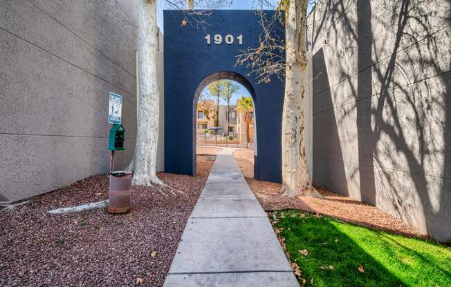 an archway with a sidewalk and trees in front of a building
