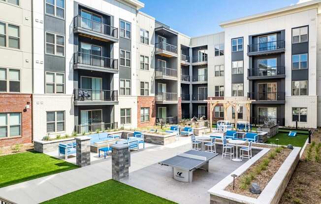 A sunny day at a modern apartment complex with a large outdoor seating area.