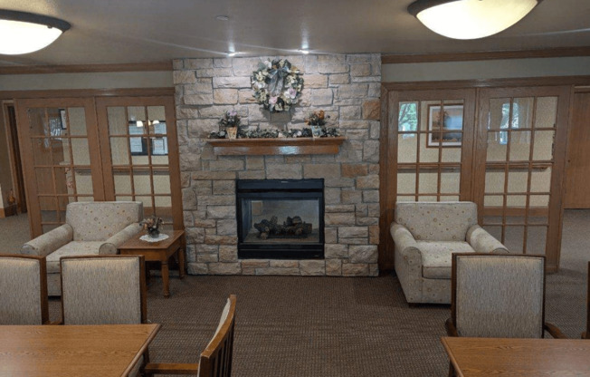 a living room with a stone fireplace and a table and chairs