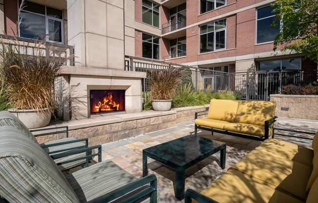 A patio with a fireplace, chairs, and a table.