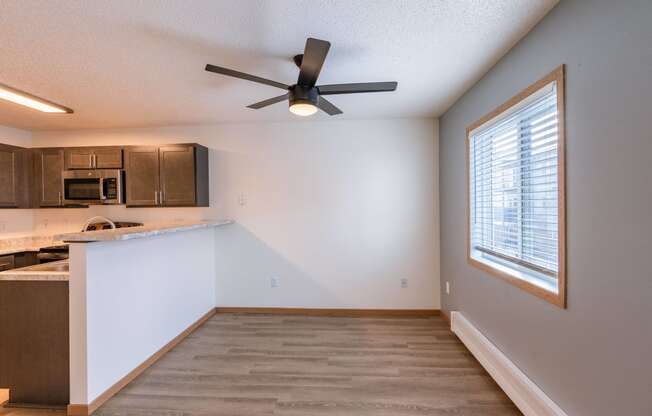 an empty kitchen with a ceiling fan and a window. Fargo, ND Sunwood Apartments